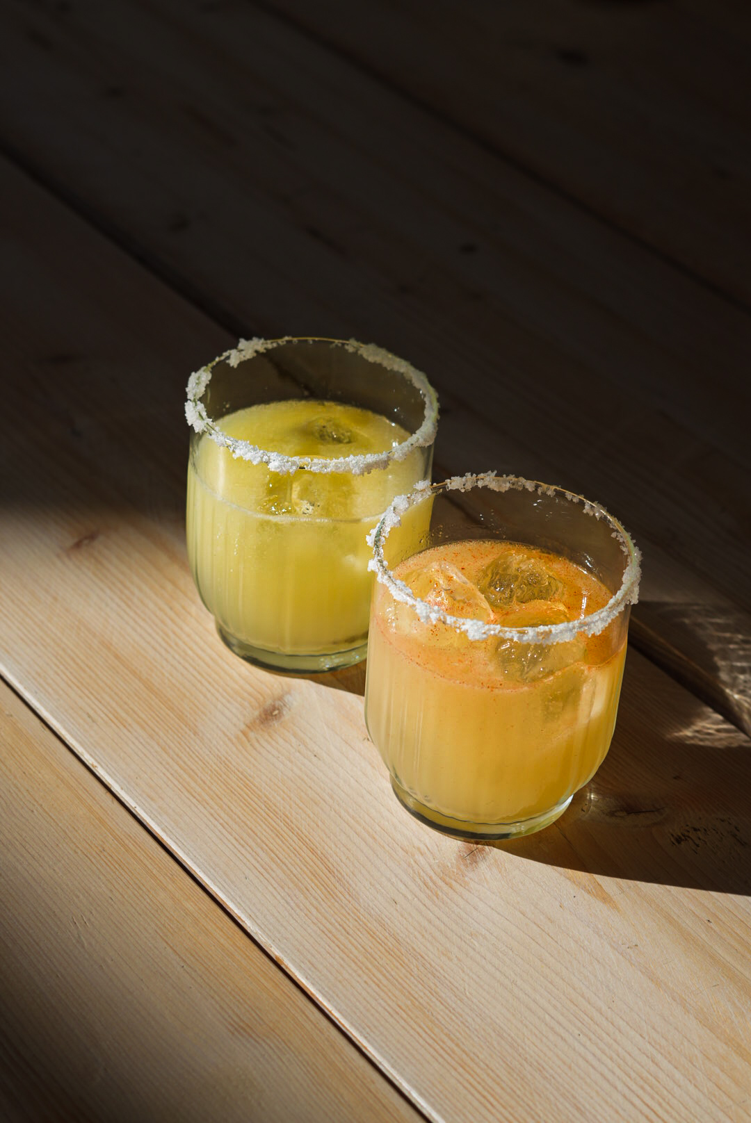 Two salt-rimmed margaritas catching afternoon sun