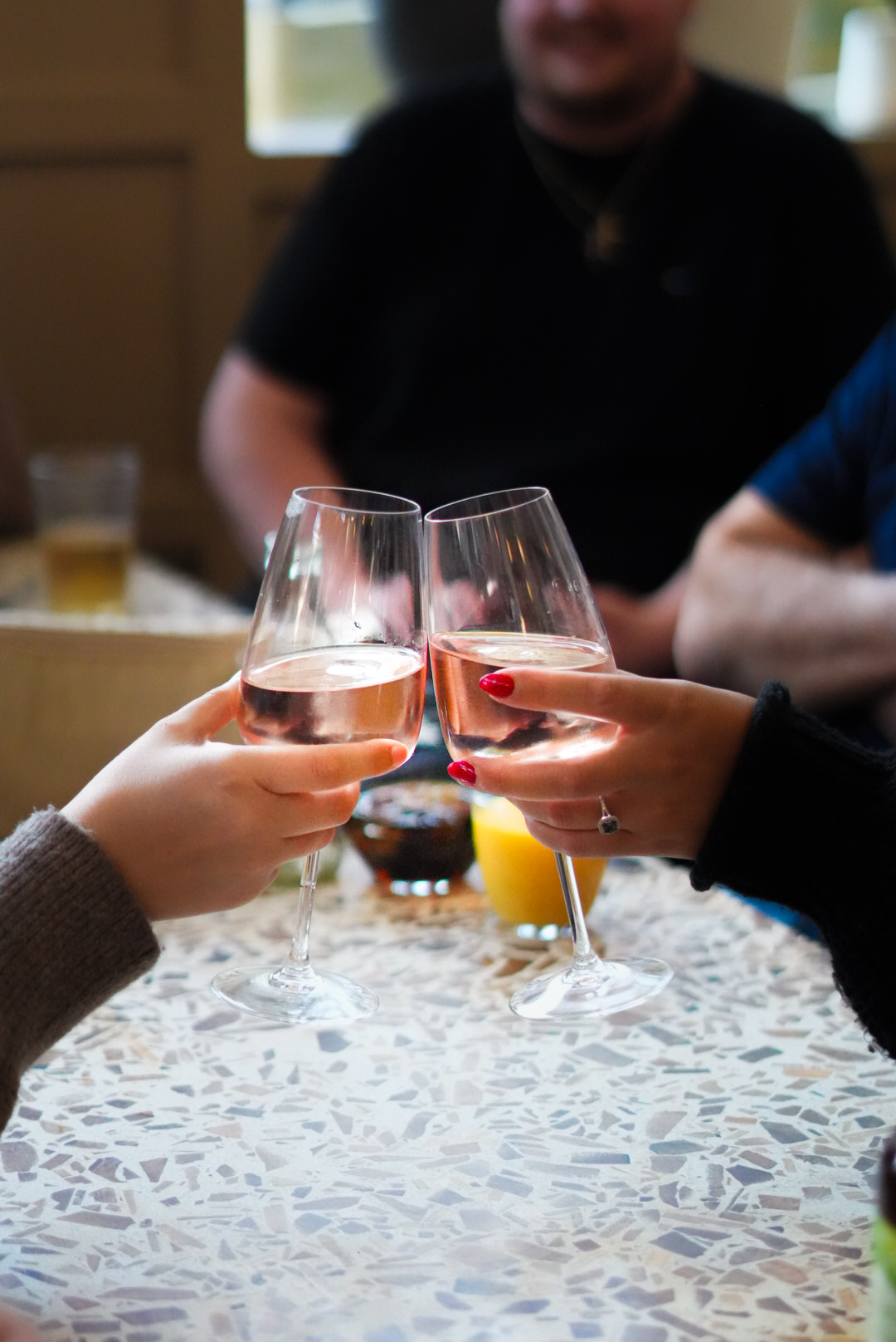 Two glasses of rosé clinking over a terrazzo table
