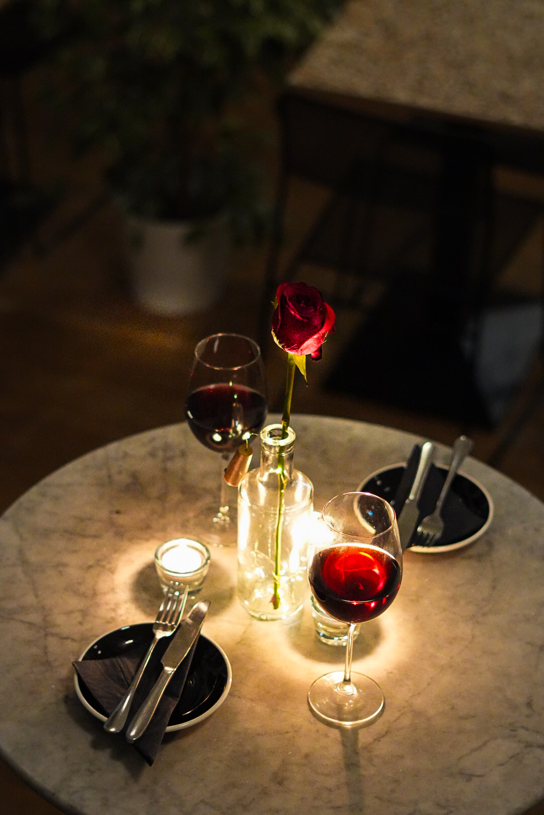 Marble bistro table set for dinner with wine and rose