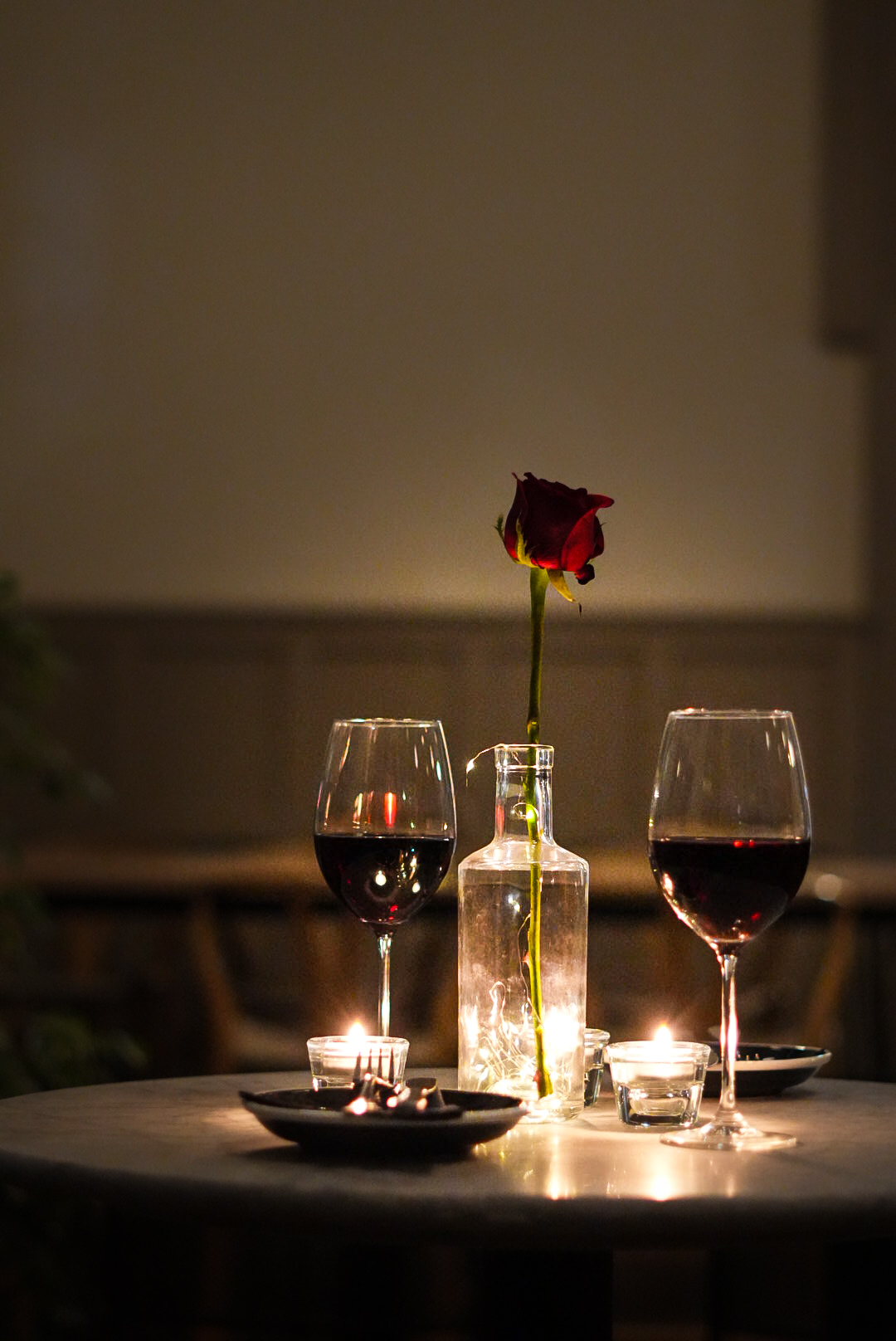 Two glasses of red wine with a rose