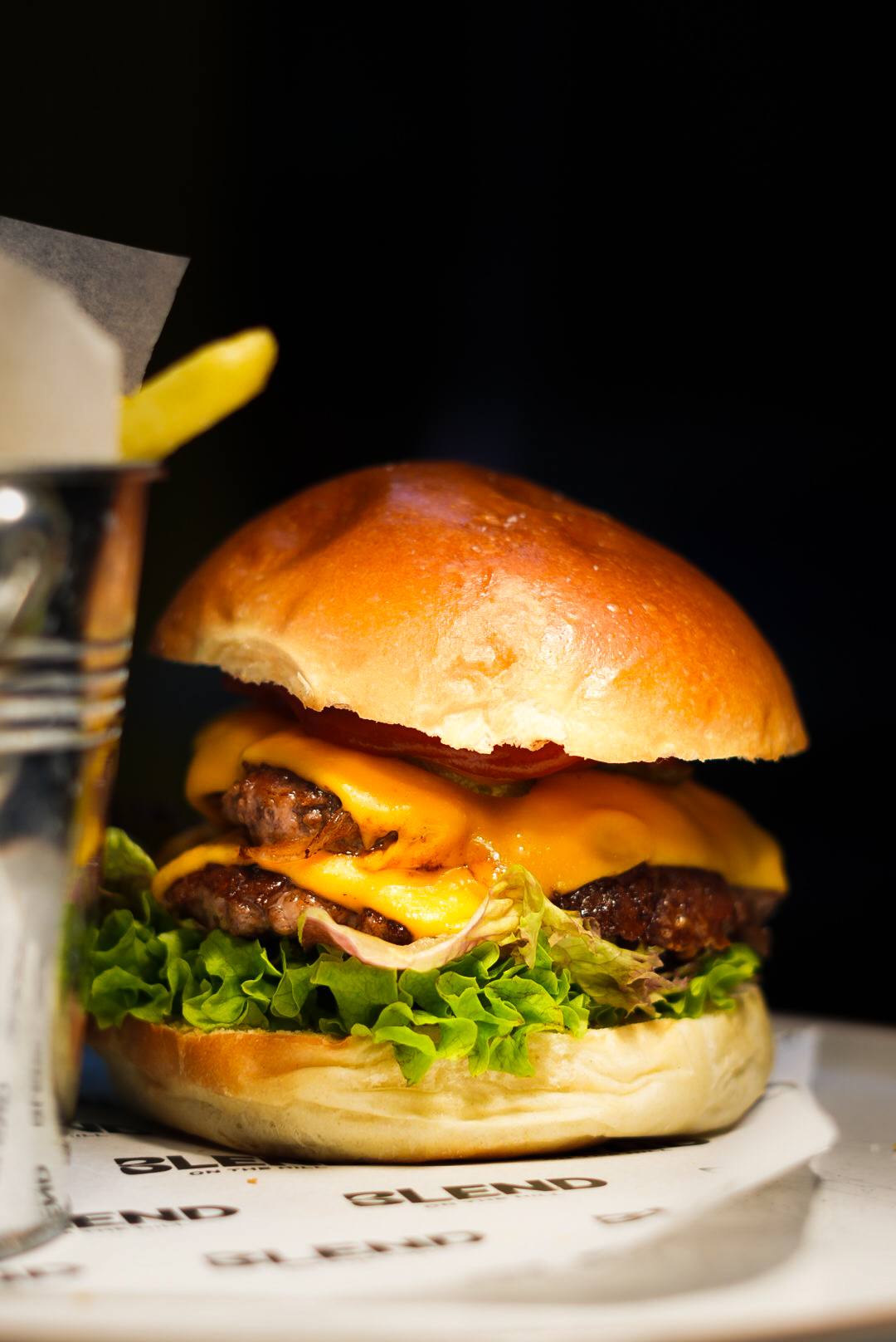 Double cheeseburger on a Blend napkin with a side of fries
