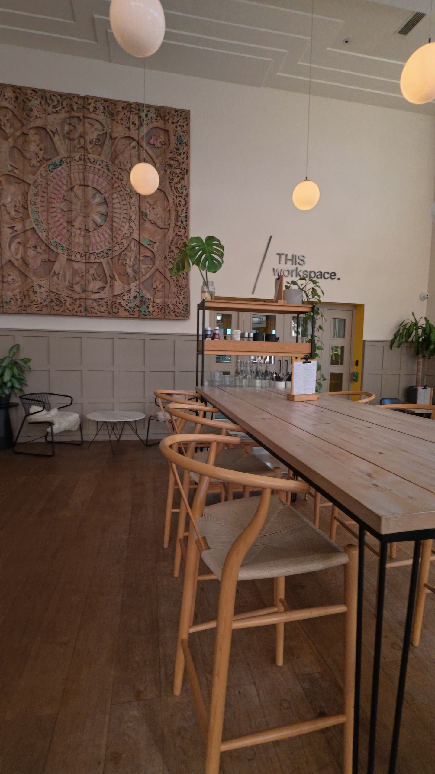 Long communal table with wishbone chairs and pendant lights